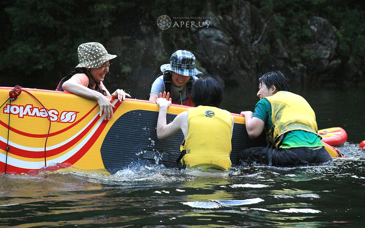 ボードにつかまって、水しぶきの中で笑う4人